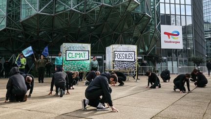 Des militants pour la défense du climat devant les bureaux de TotalEnergies à La Défense, à Courbevoie (Hauts-de-Seine), le 28 mars 2024. (THOMAS SAMSON / AFP)