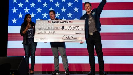 Le milliardaire Elon Musk remet un chèque d'un million de dollars à une signataire de sa pétition, le 28 octobre 2024 à Lancaster, en Pennsylvanie (Etats-Unis). (SAMUEL CORUM / GETTY IMAGES NORTH AMERICA / AFP)