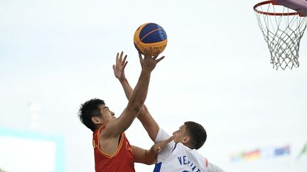 Le joueur chinois Lu Wenbo face à la défense de Timothé Vergiat lors du match de basketball 3x3 olympique contre la France, le 4 août 2024, à Paris. (LUIS ROBAYO / AFP)