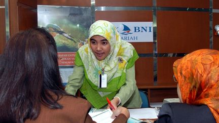 Une employée indonésienne de la division islamique de la Bank Negara Indonesia avec deux clientes (2003). (AFP PHOTO / ADEK BERRY)