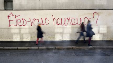 Des personnes passent devant un graffiti sur lequel on peut lire "Êtes-vous heureux ?" dans la ville de Rennes, le 24 octobre 2016. (DAMIEN MEYER / AFP)