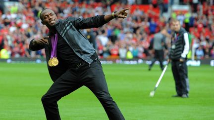 Le sprinter jama&iuml;cain Usain Bolt prend la pose sur la pelouse du stade de Manchester, avant la rencontre de Premier League entre Manchester United et Fulham, le 25 ao&ucirc;t 2012.&nbsp; (ANDREW YATES / AFP)