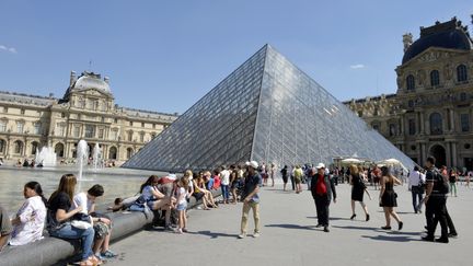 Des visiteurs profitent du soleil pr&egrave;s de la pyramide du mus&eacute;e du Louvre, le 3 juillet 2014, &agrave; Paris.&nbsp; (MIGUEL MEDINA / AFP)