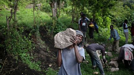 les Bambuti travaillent dans les champs des propriétaires terriens havu, qui les traitent souvent avec mépris et les rémunèrent moins que les autres travailleurs. Ce que confirme Habimana qui désherbe un terrain sur lequel un homme d'affaires havu veut construire un hôtel. Elle ne gagne qu’un tiers du salaire des autres employés et pour compléter ses revenus, elle vend des poteries au marché. (Therese Di Campo/Reuters)