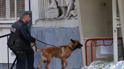 Un policier français entre avec un chien policier dans le lycée Gambetta à Arras après son évacuation après une alerte à la bombe, le 16 octobre 2023. (DENIS CHARLET / AFP)