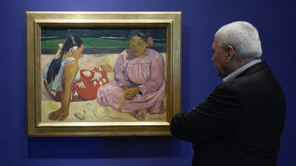 Un homme devant "Femmes de Tahiti" ou "Sur la plage" à la Fondation Mapfre à Barcelone (Espagne), le 9 octobre&nbsp; 2015. (JOSEP LAGO / AFP)