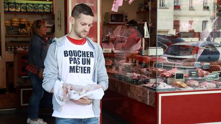 Un membre du mouvement Boucherie Abolition porte un cochonnet mort devant une boucherie, à Paris, le 22 septembre 2018. (JACQUES DEMARTHON / AFP)