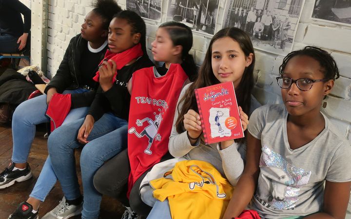 Lina et Djeinaba, élèves au collège Georges Rouault (Paris 19e), posent avec "Le journal d'un dégonflé", de Jeff Kinney (Seuil Jeunesse), le 10 décembre 2019 (Laurence Houot / franeinfo Culture)