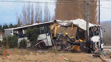 Des personnes interviennent sur le site d'une collision entre un car scolaire et un TER, le 15 décembre 2017, à Millas (Pyrénées-Orientales). (RAYMOND ROIG / AFP)