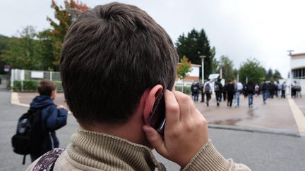 Un élève avec son téléphone portable à la main devant son collège à Saint Etienne (Loire). (ESSERTEL CLAUDE / MAXPPP)