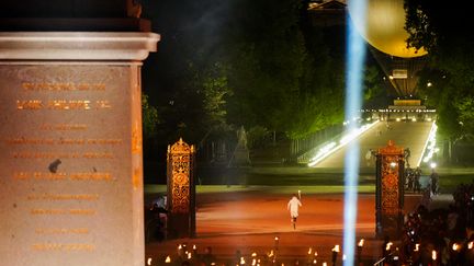 Le para-athlète allemand Markus Rehm, triple champion paralympique de saut en longueur, porte la flamme olympique de la place de la Concorde vers le Jardin des Tuileries, suivi par d'autres porteurs de flambeaux. (DIMITAR DILKOFF / AFP)