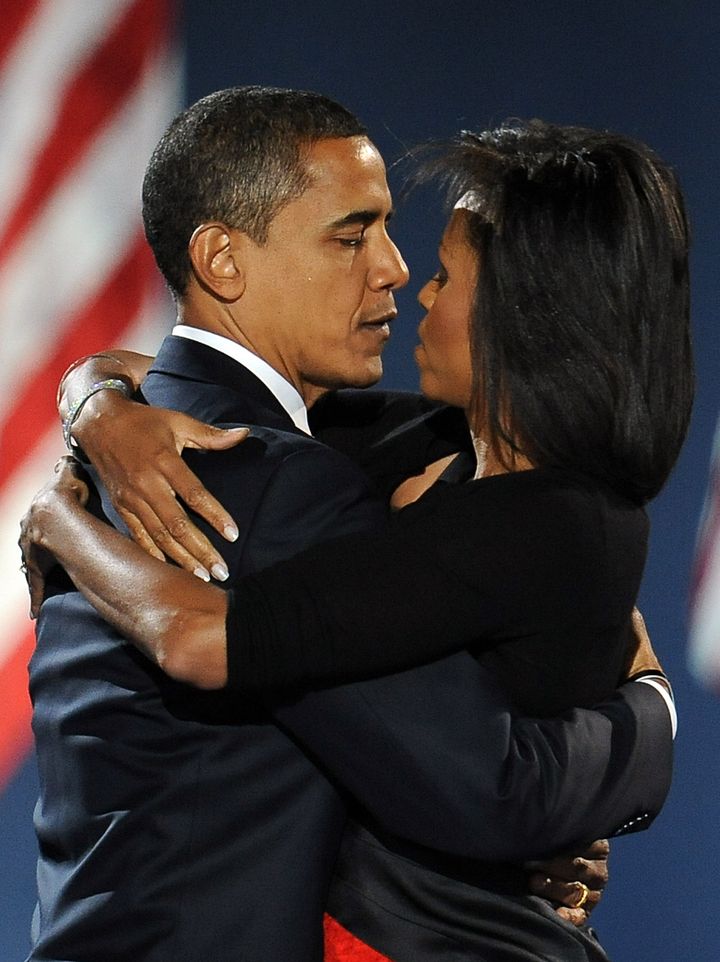 Barack Obama, qui vient d'être élu président des Etats-Unis, embrasse sa femme, devant une foule rassemblée pour fêter sa victoire, le 4 novembre 2008 à Chicago. (STAN HONDA / AFP)