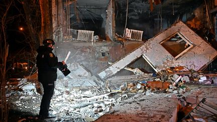 Un policier inspecte les décombres laissés par une frappe russe, le 20 décembre 2024, à Kharkiv (Ukraine) (SERGEY BOBOK / AFP)