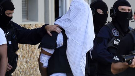 Yassin Salhi est escorté par la police à la sortie de son immeuble, le 28 juin 2015, à Saint-Priest (métropole de Lyon). (PHILIPPE DESMAZES / AFP)