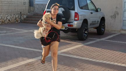 À Ashkelon, dans le sud d'Israël, une femme court vers un abri pendant une attaque à la roquette, le 10 octobre 2023. (JACK GUEZ / AFP)