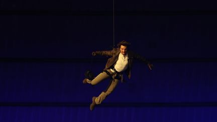 Tom Cruise prend son envol depuis le toit du Stade de France pour atterrir sur la scène et récupérer le drapeau olympique et l'amener à Los Angeles. (FRANCK FIFE / AFP)