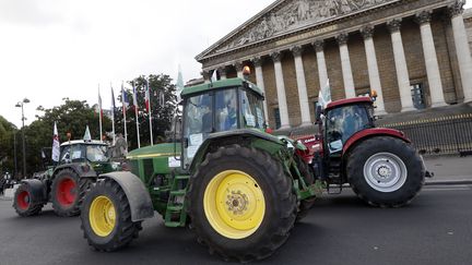 Un convoi de tracteurs passe devant l'Assembl&eacute;e nationale.&nbsp; (THOMAS SAMSON / AFP)