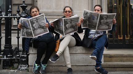 Trois touristes guatémaltèques lisent The Evening Standard,&nbsp;le principal journal gratuit de Londres (Royaume-Uni),&nbsp;au lendemain de la mort de la reine.&nbsp; (JUSTIN TALLIS / AFP)