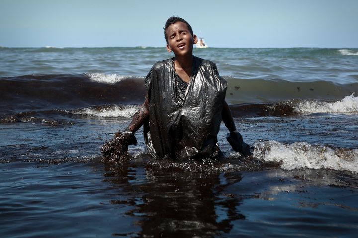 Everton Miguel dos Anjos&nbsp;sort de l'eau souillé de pétrole, lundi 21 octobre, à Cabo de Santo Agostinho, dans l'Etat du Pernambouc au Brésil. (LEO MALAFAIA / AFP)