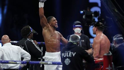 Le Britannique Anthony Joshua (à gauche) célèbre sa victoire contre le Bulgare Kubrat Pulev (à droite) lors du match de boxe pour le titre mondial des poids lourds à la Wembley Arena, au nord-ouest de Londres, le 12 décembre 2020.
 (ANDREW COULDRIDGE / POOL)