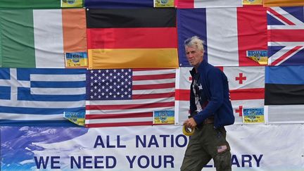 Ryan Wesley Routh brandissant les drapeaux nationaux des pays aidant l'Ukraine, sur la place de l'Indépendance, à Kiev, le 23 juin 2022. (SERGEI SUPINSKY / AFP)