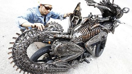 Un Tha&iuml;landais inspecte sa moto construite &agrave; partir de pi&egrave;ces r&eacute;cup&eacute;r&eacute;es sur des voitures et des v&eacute;los &agrave; Bagkok, le 27 juillet 2011. (SUKREE SUKPLANG / REUTERS)