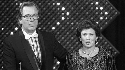 Jean Lanzi et Anne Sinclair aux 7 d'Or, les défunts Oscars de la télévision où ils avaient été récompensés pour l'hebdomadaire "7 sur 7" (TF1), le 25 octobre 1985 à Paris
 (Michel Gangne / AFP)