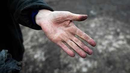 La main couverte de poussière noire d'un agriculteur, à&nbsp;Saint Martin-du-Vivier, près de Rouen (Seine-Maritime), le 30 septembre 2019, après l'incendie de l'usine Lubrizol. (LOU BENOIST / AFP)