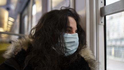 Une femme porte un masque de protection dans le RER au Plessis-Robinson (Hauts-de-Seine), le 13 décembre 2022. (MAGALI COHEN / HANS LUCAS / AFP)