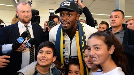 Usain Bolt pose avec des enfants à son arrivée en Australie, le 18 août 2018. (SAEED KHAN / AFP)