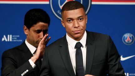 Le PDG du Paris Saint-Germain Nasser Al-Khelaifi aux côtés de Kylian Mbappé, posant avec un maillot du club, à l'issue d'une conférence de presse au Parc des Princes à Paris, le 23 mai 2022. (FRANCK FIFE / AFP)