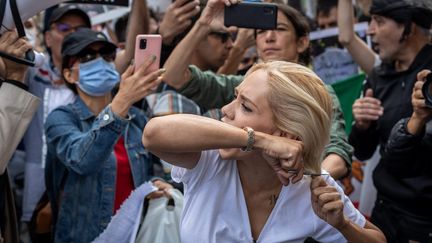 Une femme se coupe les cheveux en soutien aux femmes iraniennes, lors d'une manifestation en Turquie, le 4 octobre 2022. (TOLGA ILDUN / MAXPPP)