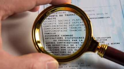 Un bulletin de paie vu à travers une loupe à Paris, le 5 février 2019. (RICCARDO MILANI / HANS LUCAS/AFP)