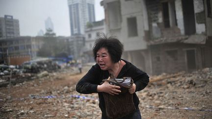 Une femme dont la maison s'appr&ecirc;te &agrave; &ecirc;tre d&eacute;molie jette des pierres sur les ouvriers &agrave; Guangzhou (Chine), le 21 mars 2012. (REUTERS)