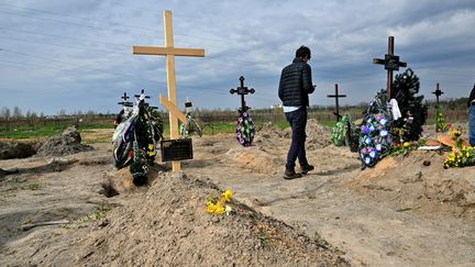 Un homme passe devant&nbsp;une tombe dans le cimetière de Bucha en Ukraine, le 25 avril 2022. Photo d'illlustration. (SERGEI SUPINSKY / AFP)