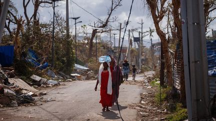 Une femme transporte de l'eau à Pamandzi (Mayotte), le 17 décembre 2024. (DIMITAR DILKOFF / AFP)