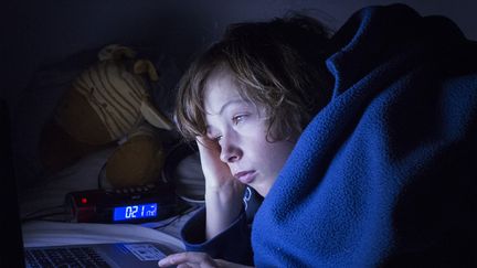 Un adolescent, dans son lit, regarde un écran, le 15 mars 2021, à Toulouse (Haute-Garonne). (ARNAUD CHOCHON / HANS LUCAS / AFP)