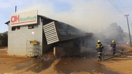 Les pompiers éteignent le feu qui a détruit un supermarché de Manzini, le 30 juin 2021. Les manifestations se sont multipliées dans tout&nbsp;l'eSwatini ces derniers jours pour réclamer une véritable démocratie. Selon un dernier bilan fourni par les activistes, huit personnes auraient été tuées. (- / AFP)