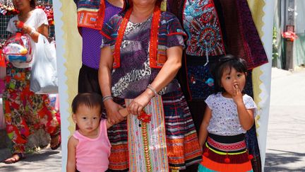 Dow Wasiksiri photographie les Thaïlandais dans leurs diversité d'habillement sur un marché de Chiangmai. Il y emprunte des toiles cirées colorées pour servir de fond à un studio improvisé. Elles sont plus ou moins assorties aux tenues des sujets pour créer un patchwork de couleurs. Le photographe aime que la foule participe : les passants sont souvent sollicités pour tenir la toile. Il ne resserre pas l'image sur les portraits, y incluant tout le monde.
 (Dow Wasiksiri © musée du quai Branly, Photoquai 2013)