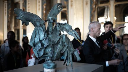 Le coq de la flèche de Notre-Dame exposé au ministère de la Culture, alors qu'à quelques mètres, le ministre Franck Riester présente l'exposition "Revoir Notre-Dame", le 20 septembre 2019 à Paris. (PHILIPPE LOPEZ / AFP)