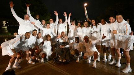 Les derniers relayeurs de la flamme réunis autour de l'ancien cycliste Charles Coste, 100 ans, plus vieux champion olympique français encore vivant. (MOHD RASFAN / AFP)