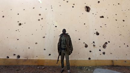 Un soldat malien se tient devant un mur cribl&eacute; de balles lors de la lib&eacute;ration de Konna, le 26 janvier 2013. (ERIC GAILLARD  / REUTERS)