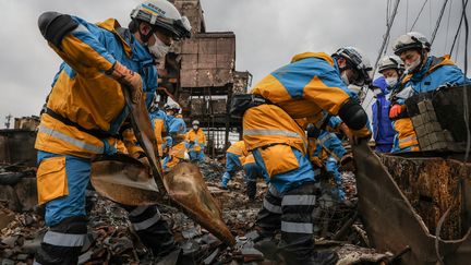 Des officiers de police cherchent une personne disparue à Wajima, le 10 janvier 2024, dans la région de Noto, touchée par le séisme qui a frappé le Japon le 1er janvier. (STR / JIJI PRESS / AFP)