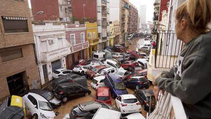 Une femme observe des véhicules emportés par les flots depuis son balcon à Valence (Espagne), le 30 octobre 2024. (ALBERTO SAIZ / AP / SIPA)