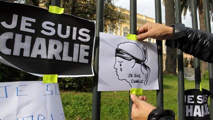 Un homme attache une pancarte sur les grilles de la pr&eacute;fecture de la&nbsp;Corse-du-Sud &agrave; Ajaccio, apr&egrave;s la minute de silence. (PASCAL POCHARD-CASABIANCA / AFP)