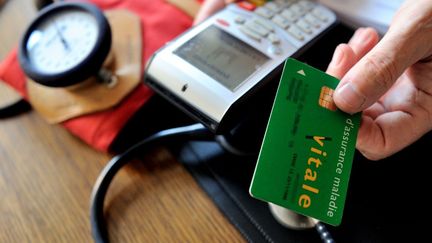 Un médecin tend à un patient sa carte vitale, à&nbsp;Godewaersvelde (Nord). (PHILIPPE HUGUEN / AFP)