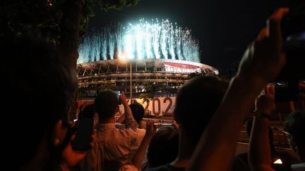 La cérémonie d'ouverture a commencé par un feu d'artifice tiré depuis le Stade olympique national de Tokyo, à 13 heures, heure française. Un lancement symbolique pour célébrer ces Jeux olympiques (23 juillet-8 août) sans public dans l'enceinte, avec une population obligée de se regrouper à l'extérieur, à cause de la situation sanitaire au Japon.&nbsp; (BEHROUZ MEHRI / AFP)