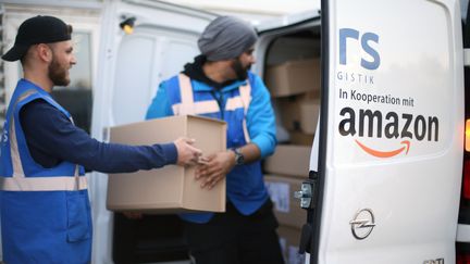 Des livreurs chargent une camionnette Amazon. (INA FASSBENDER / DPA)