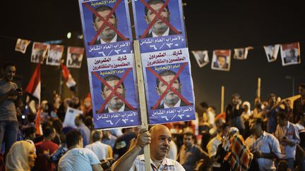 Un Egyptien brandit une pancarte&nbsp;anti-Morsi place Tahrir, au Caire, le 26 juin 2013. (GIANLUIGI GUERCIA / AFP)