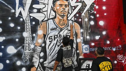 L'artiste Michael Sanchez (à droite) et le designer Soy Empire devant la fresque murale de Wembanyama à San Antonio, Texas, le 23 octobre 2023. (CHANDAN KHANNA / AFP)